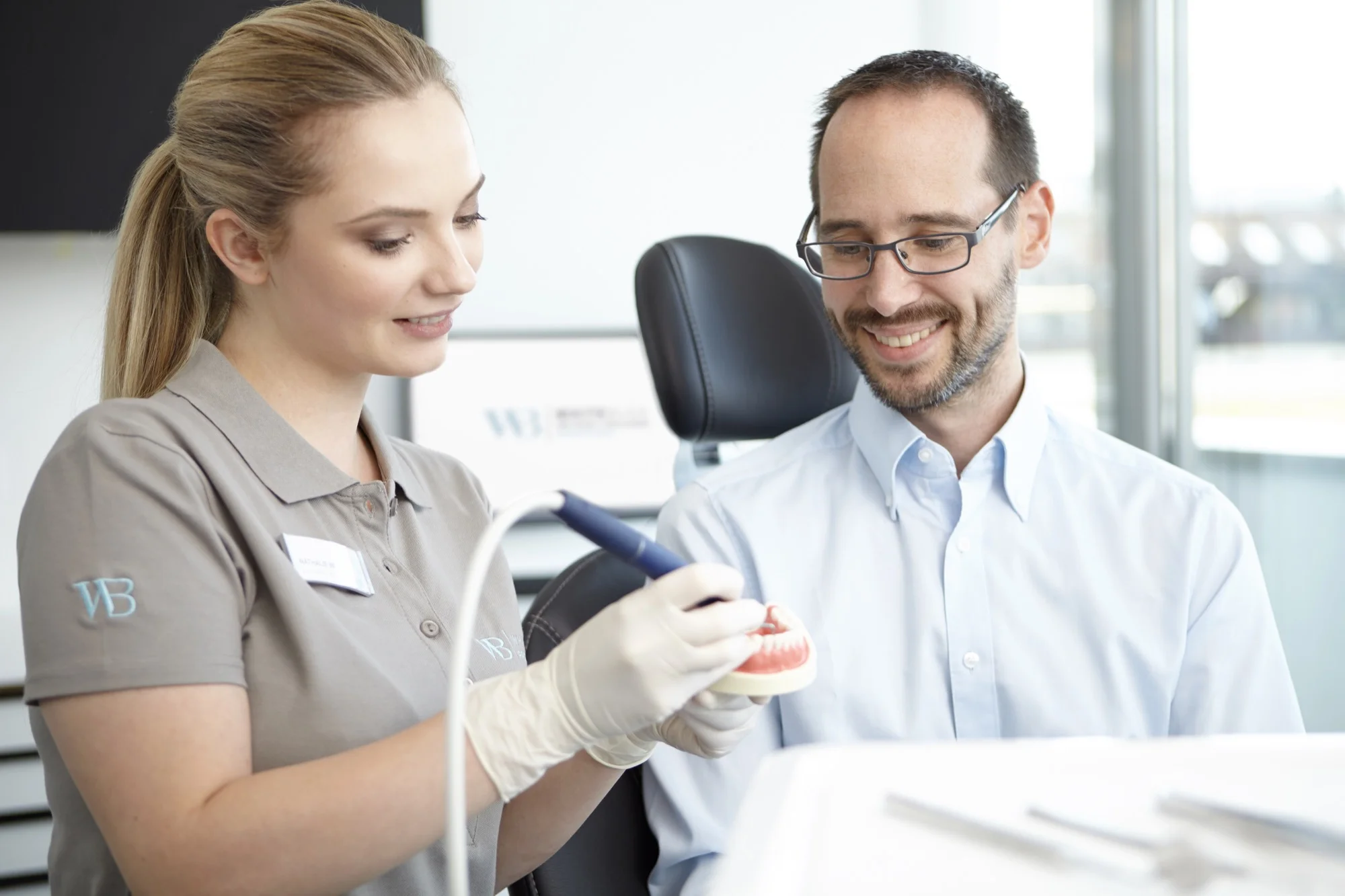 WHITEBLICK-Prophylaxeassistentin erklärt Patienten das Vorgehen bei der Professionellen Zahnreinigung.