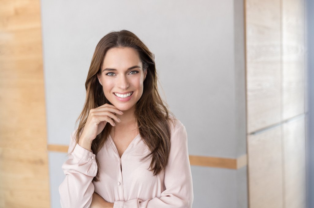 whiteblick-weisse-zaehne Eine braunhaarige Frau mit schönen weißen Zähnen lächelt in die Kamera.